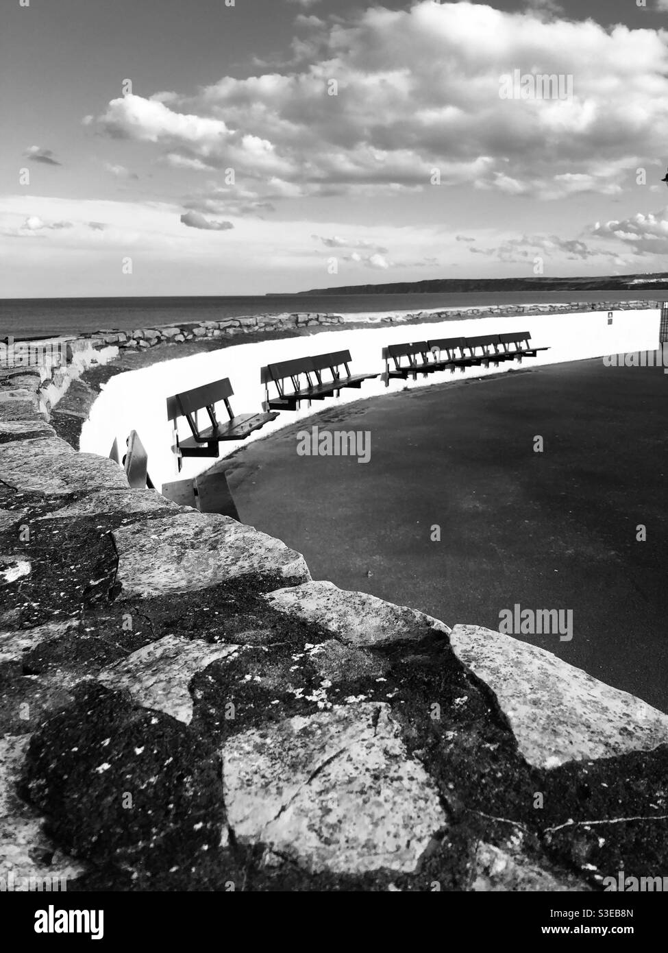 Black and white image of an empty seating area at the seaside during lockdown - Smartphone Captured Stock Image