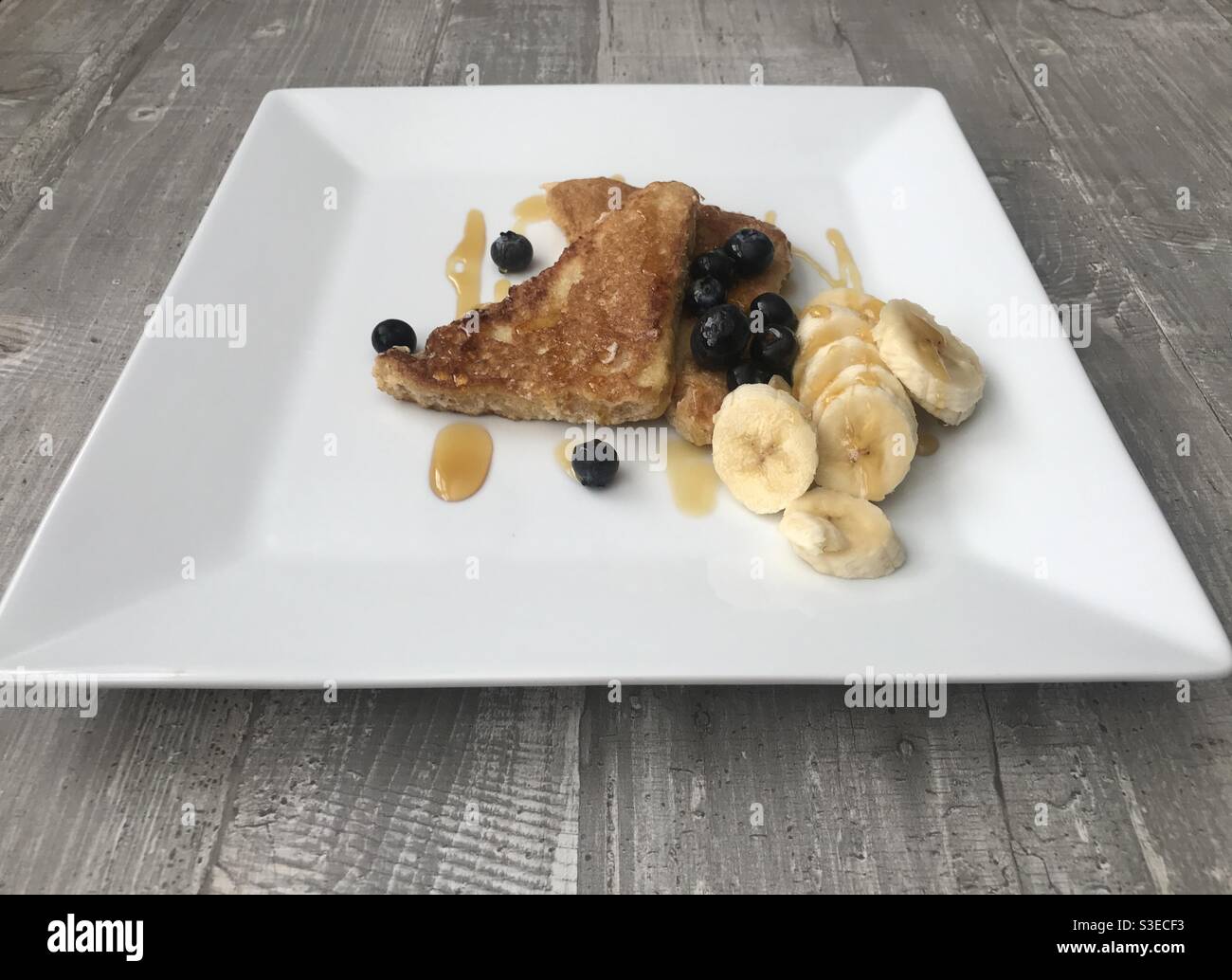 Cinnamon French toast served with sliced banana and blueberries and topped with maple syrup - Smartphone Captured Stock Image
