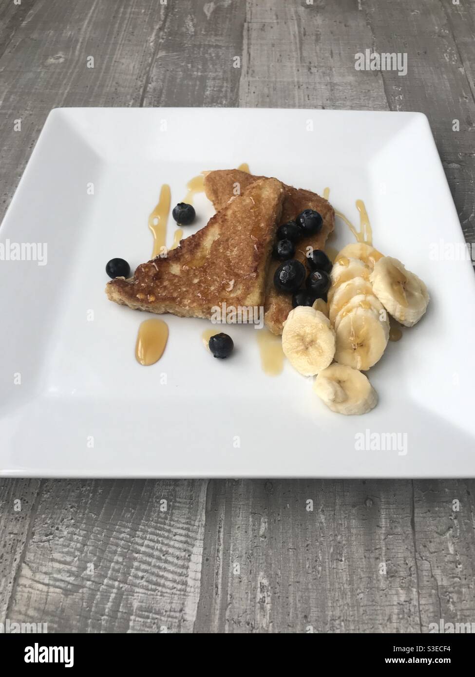 Cinnamon French toast served with sliced banana and blueberries and topped with maple syrup - Smartphone Captured Stock Image
