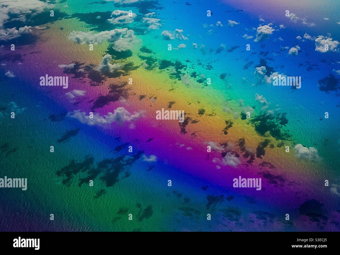 Aerial: refracted clouds in a rainbow of colours. Photographed at 10000 meters. Concepts: rainbows, floating free, light, spectrum, refraction, Joy, abandon, surreal, phantasy, dreamy, drifting - Smartphone Captured Stock Image