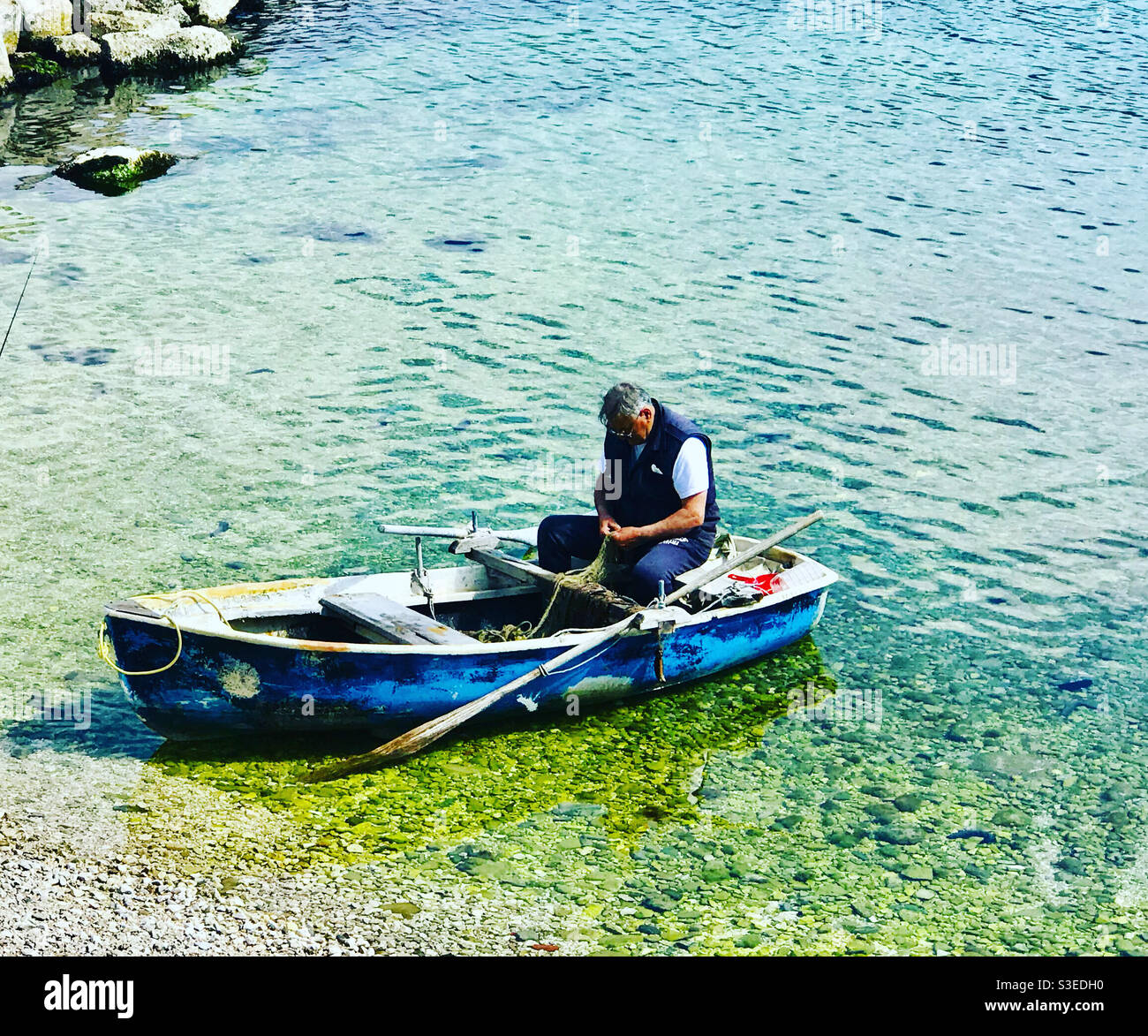 A fisherman preparing his nets in a boat in Stobrec, Croatia - Smartphone Captured Stock Image