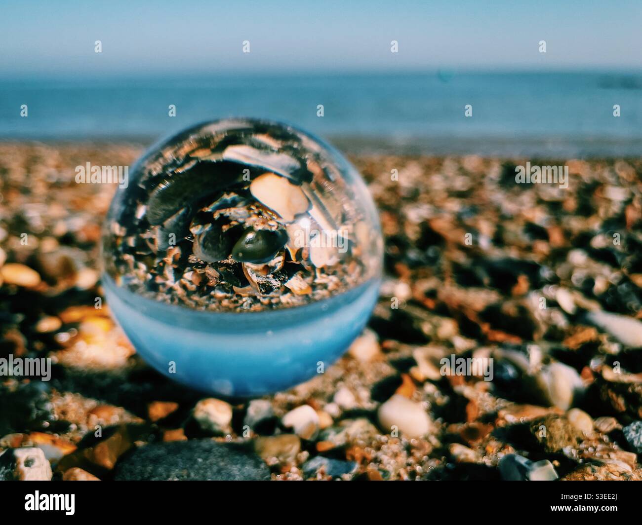 Glass ball on stone pebble beach - Smartphone Captured Stock Image