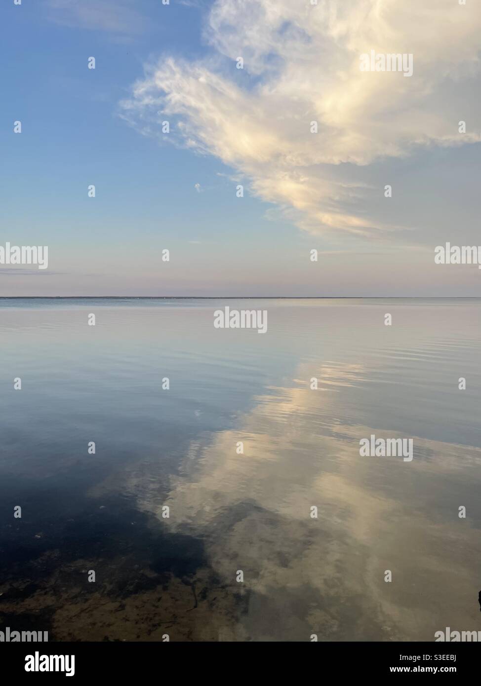 Early evening sunset clouds reflecting onto calm bay water - Smartphone Captured Stock Image