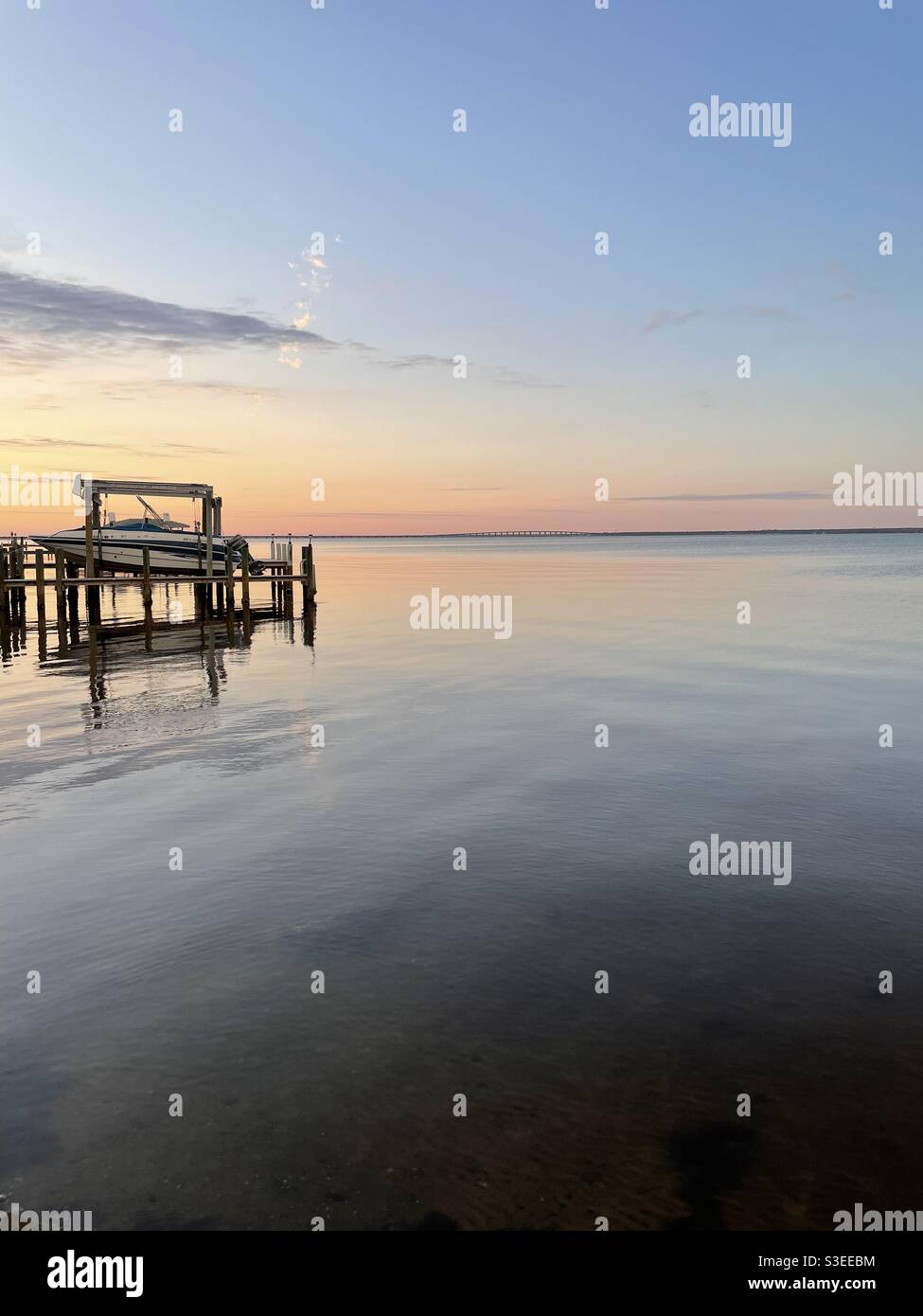 Soft evening sunset skies over still bay water with a boat docked - Smartphone Captured Stock Image