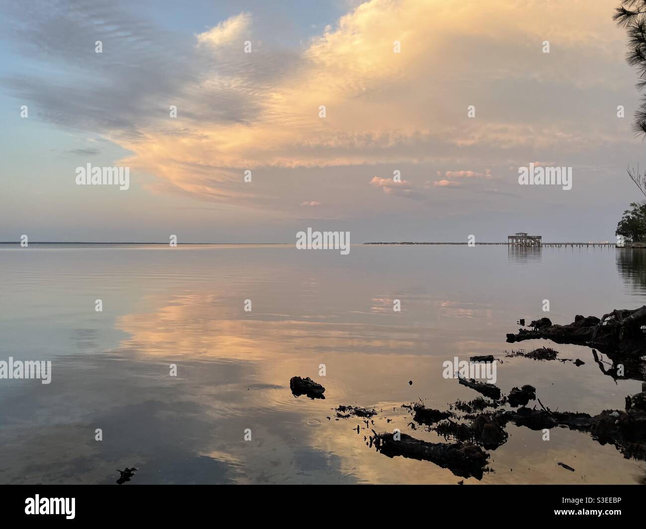 Bright sunset clouds reflecting onto bay water Stock Photo - Alamy