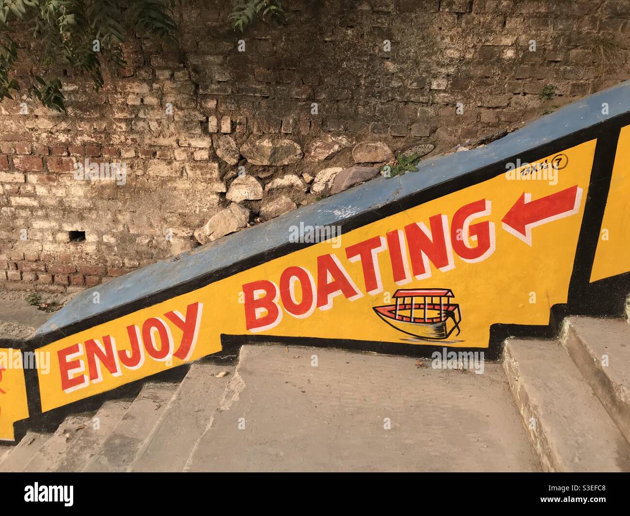“Enjoy Boating” signage on a staircase leading to the Ganges River in Rishikesh, Uttarakhand, India - Smartphone Captured Stock Image