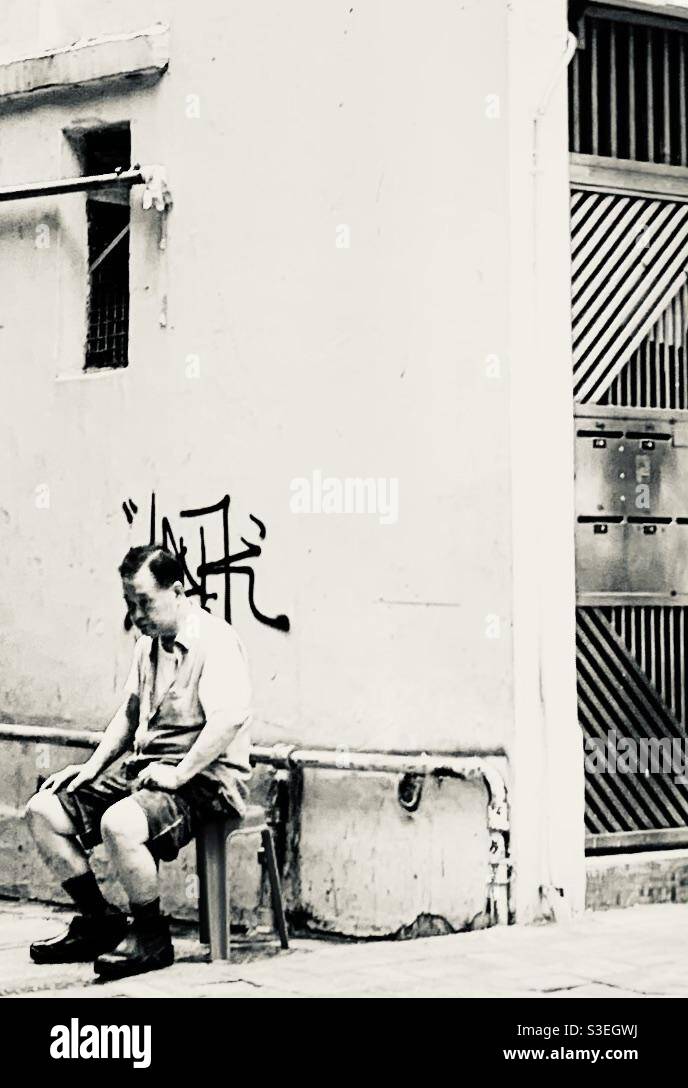 A Chinese man resting in a side street in Kennedy town in Hong Kong. Stock Photo