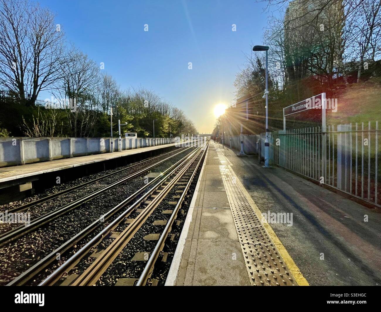 Empty train platform at plumstead south east london early morning during the Covid-19 pandemic. A couple of commuters in the distance Stock Photo