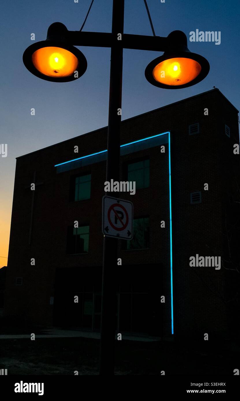 Lights composition, showing a geometry of lights — round, L-shape, and rectangular — with a warm glow in the sky. Concepts: balance, warmth, modernity, man made, lightscape. - Smartphone Captured Stock Image