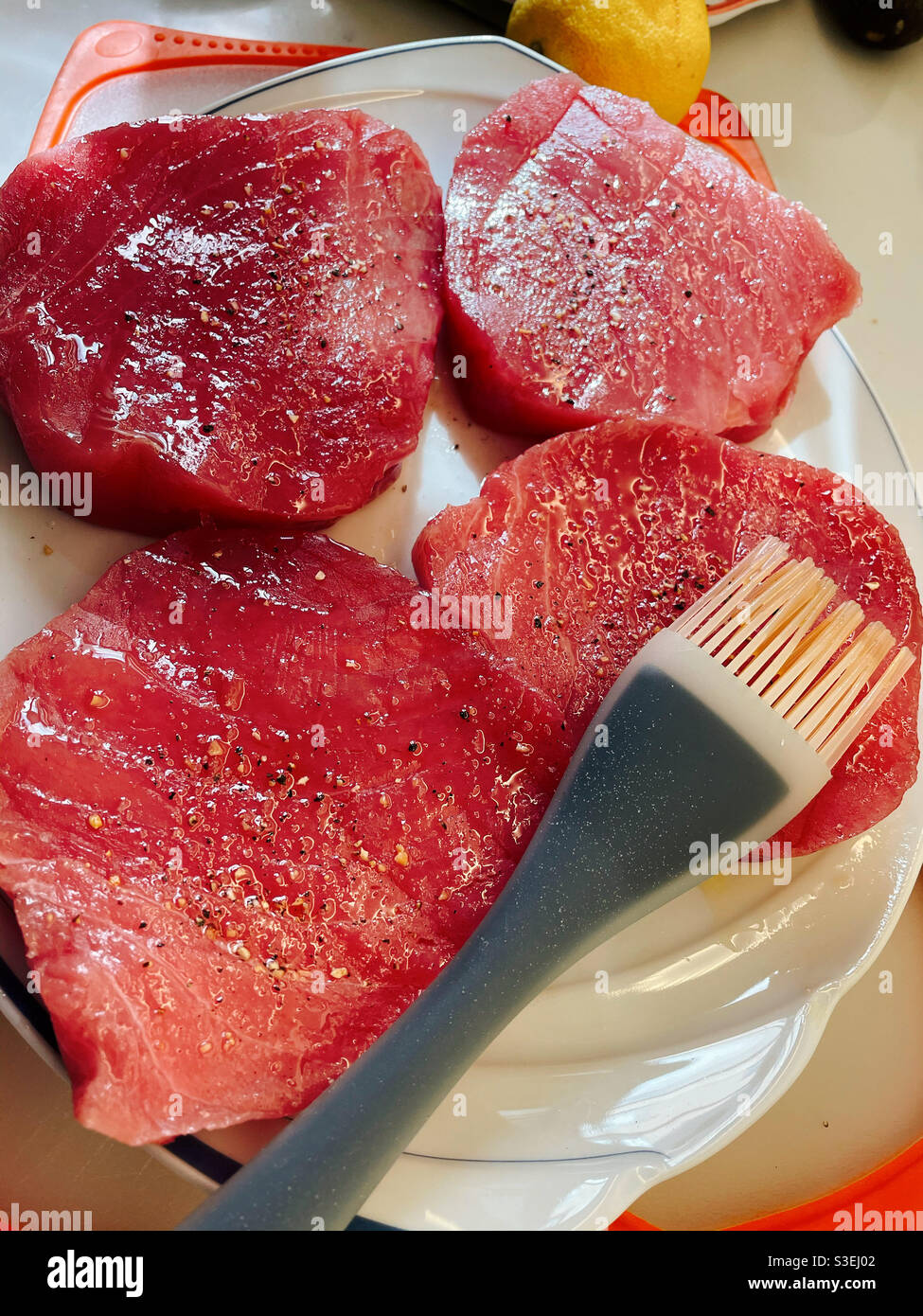 Sushi grade tuna steaks and basting brush on a serving platter - Smartphone Captured Stock Image