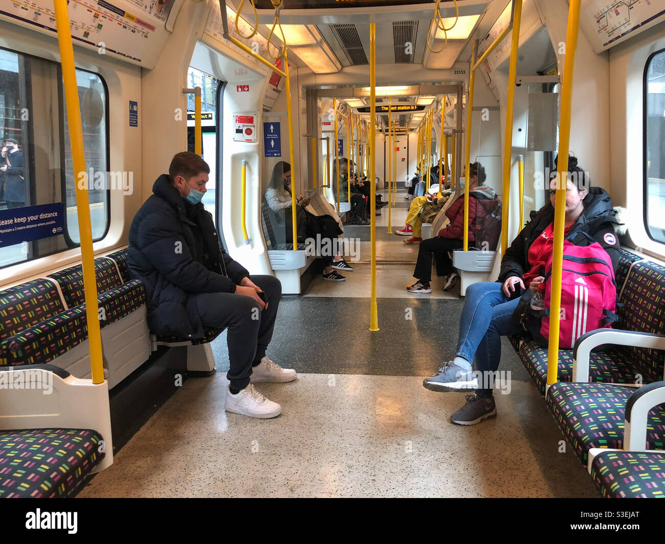 People Onboard A District Line Train In The London Underground Wear 