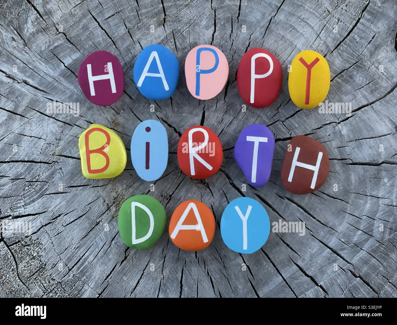 Happy Birthday composed with multi colored stone letters on a log of wood - Smartphone Captured Stock Image