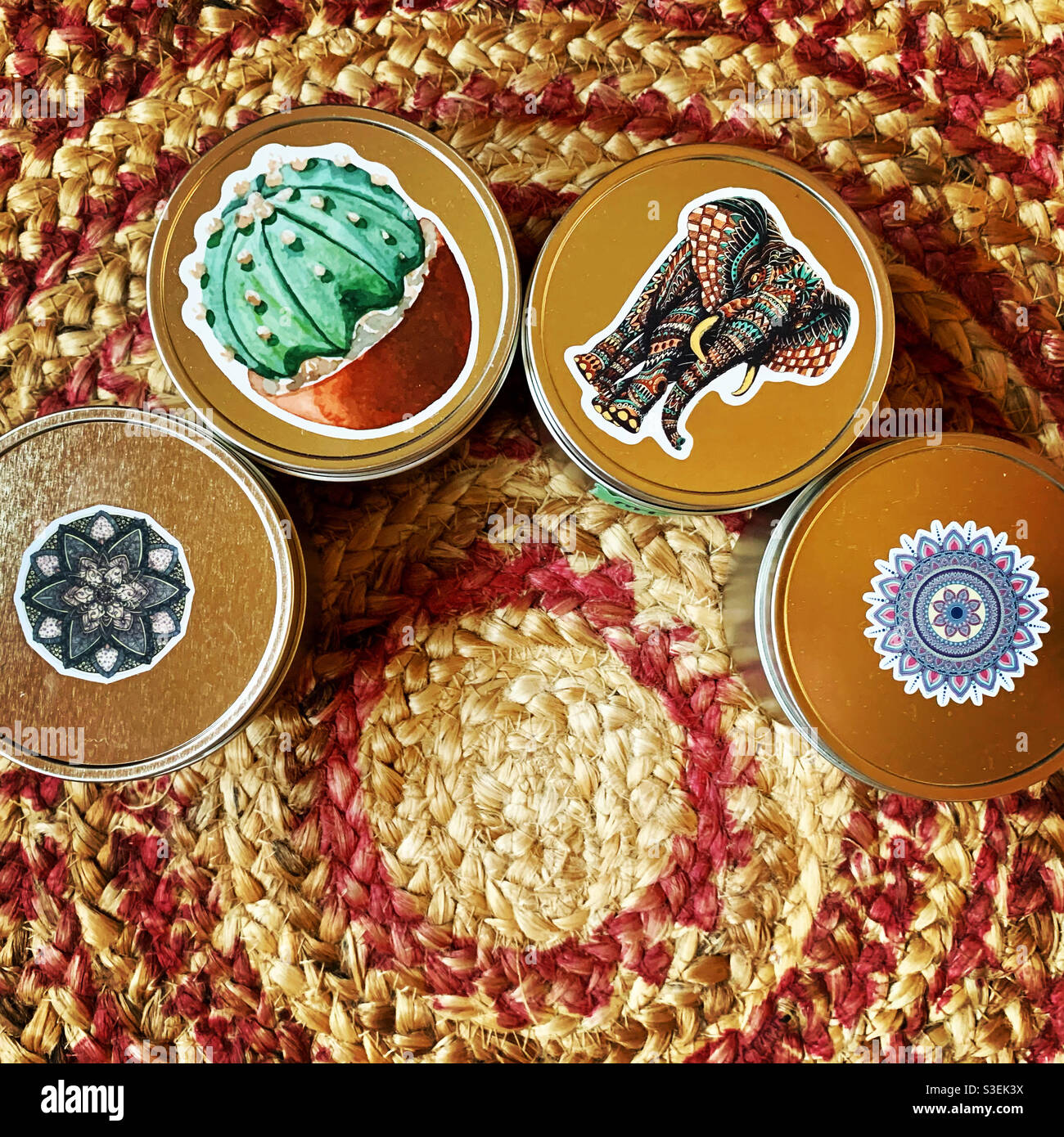 Bohemian retro themed candles with lids & tins on a bohemian pink straw rug Stock Photo