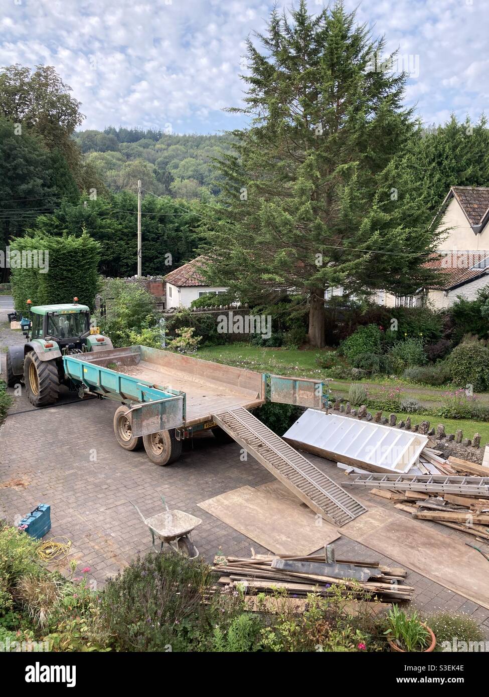 Building renovation with a tractor and trailer on the drive loading waste rubble and building materials from groundwork. Stock Photo