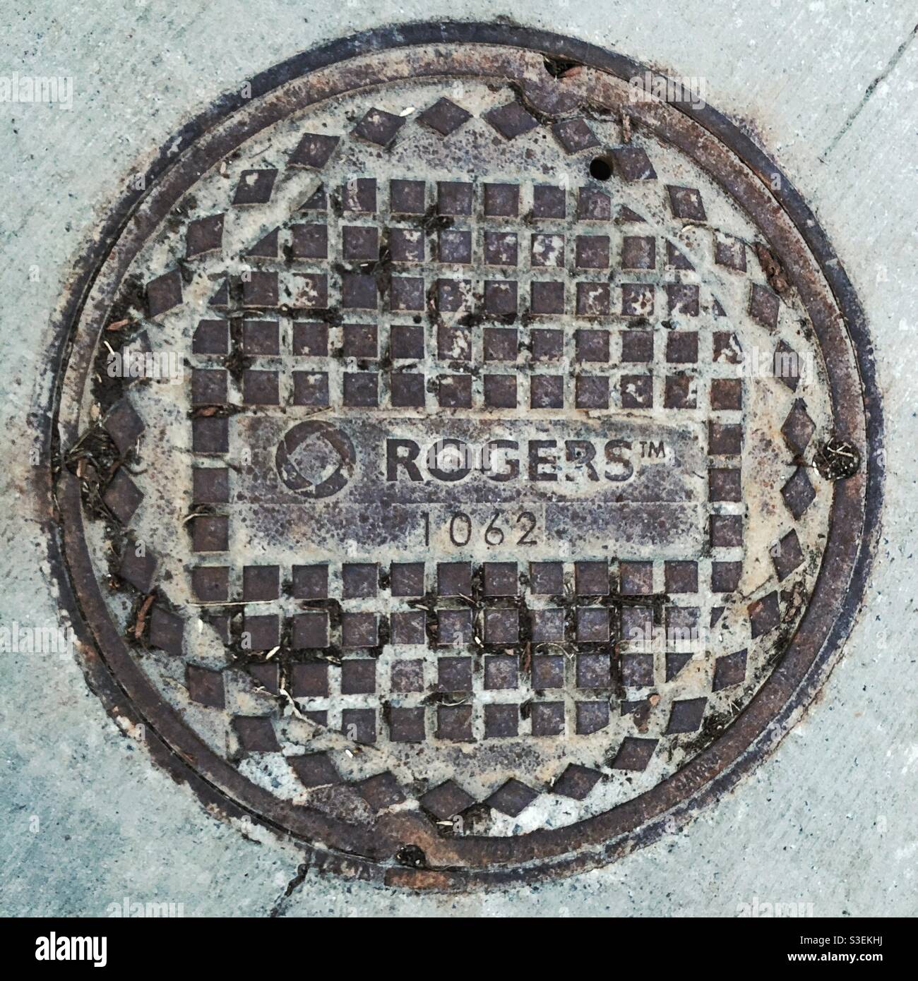 Manhole cover with RogersTM logo. Rogers is communication business, dealing with phone, Internet and TV in Canada, 2021 - Smartphone Captured Stock Image