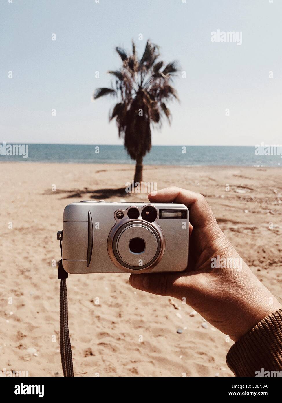 Man holding a point and shoot camera by the beach - Smartphone Captured Stock Image