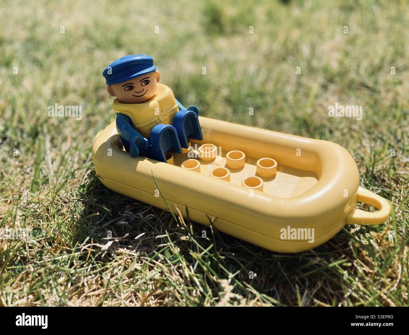 Lego Duplo toy man to the stern of a yellow inflatable life raft boat  wearing a blue hat and a yellow buoyancy aid on the grass Stock Photo -  Alamy