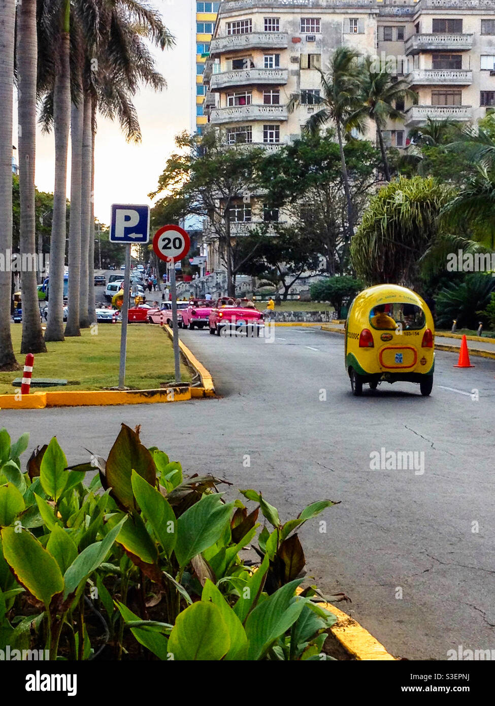 Yellow Coco taxi and vintage American cars leaving National Hotel, Havana, Cuba Stock Photo