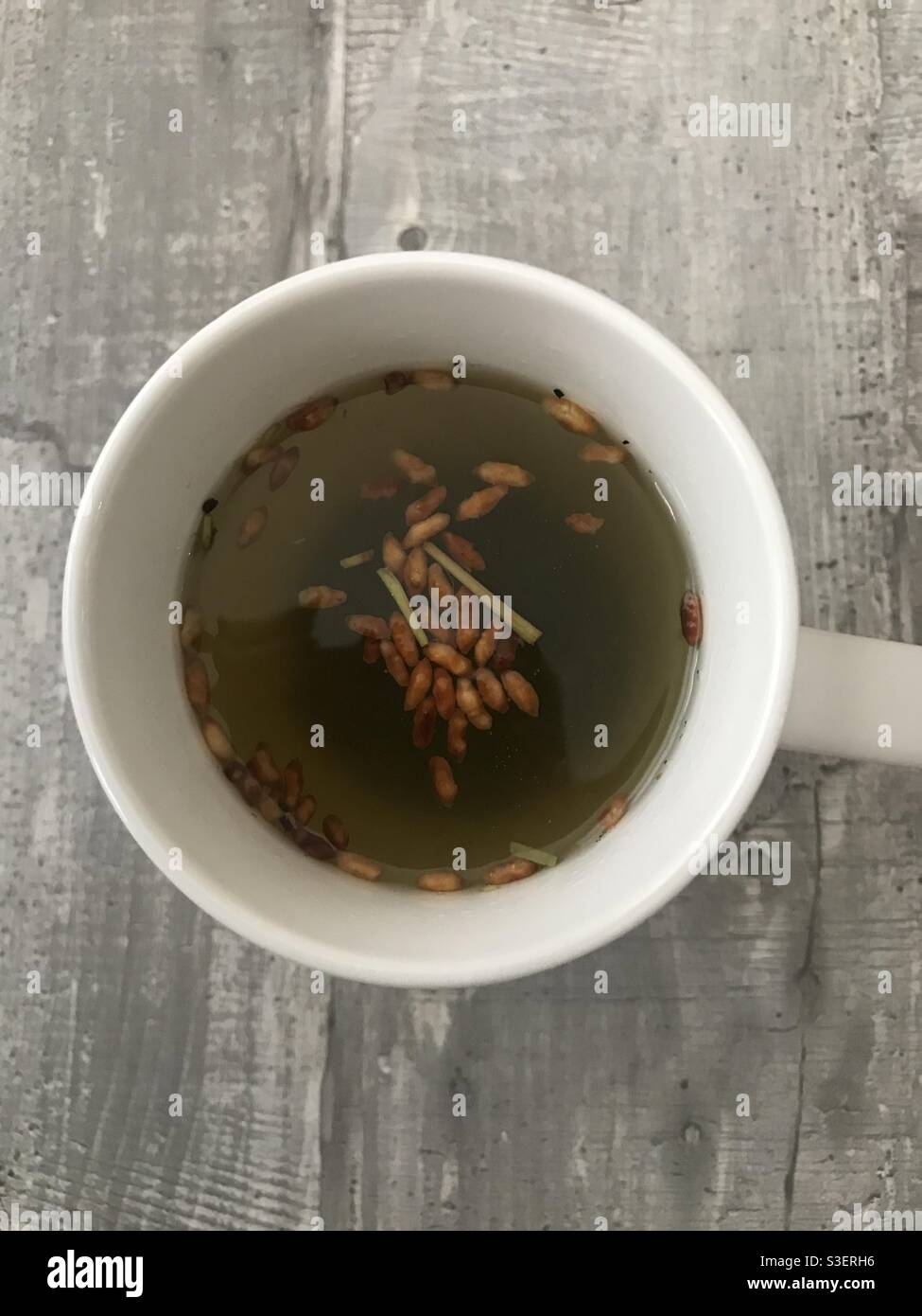 A freshly brewed cup of genmaicha Japanese brown rice green tea against a wooden background - Smartphone Captured Stock Image