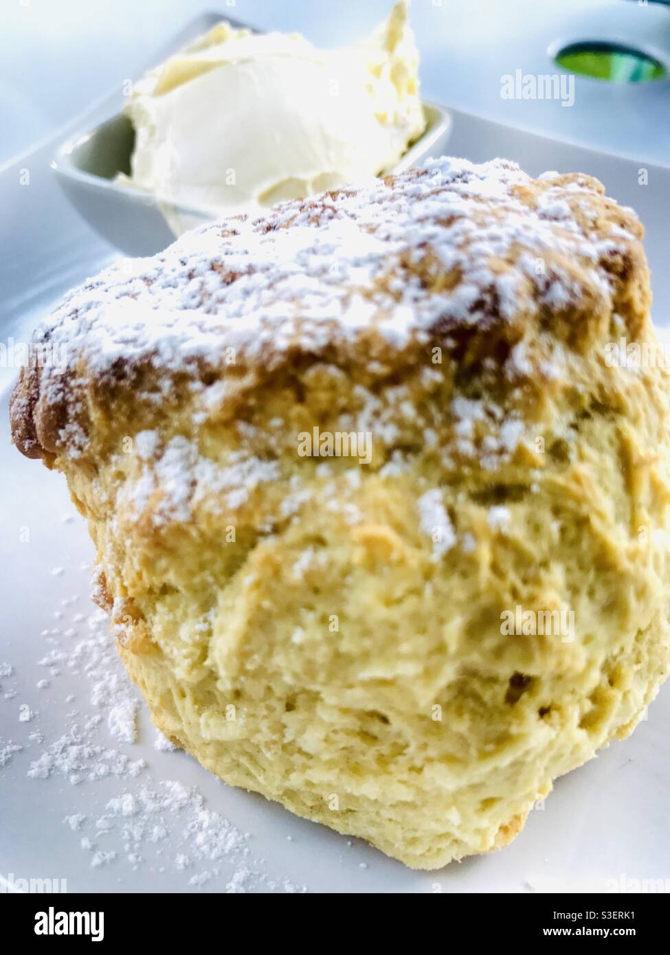 Closeup view of a freshly baked scone with Cornish clotted cream in the background Stock Photo