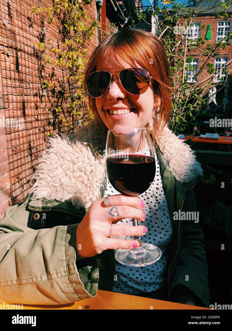 A woman enjoys a drink in a beer garden after lockdown eases - Smartphone Captured Stock Image