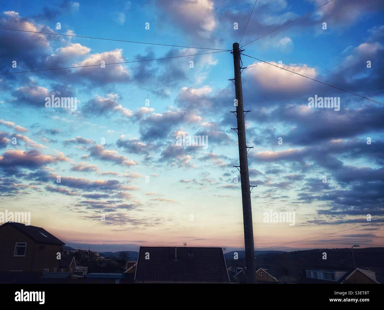 A filtered photograph of clouds at dusk about residential street with power lines - Smartphone Captured Stock Image
