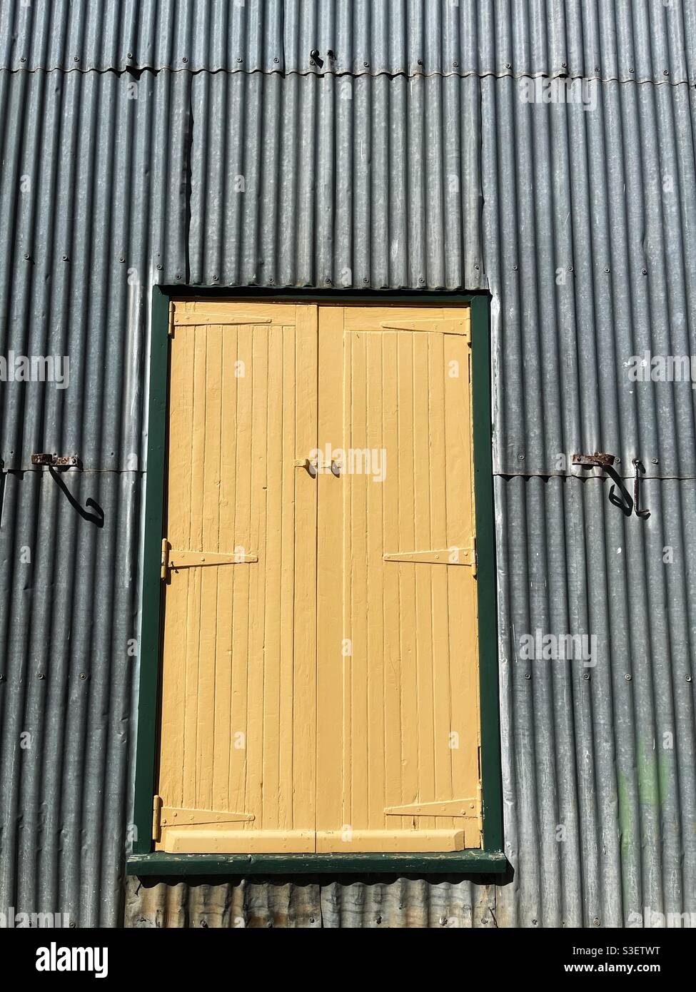 Yellow door in a corrugated iron exterior wall at the Pioneer Village in Inverell, New South Wales, Australia - Smartphone Captured Stock Image