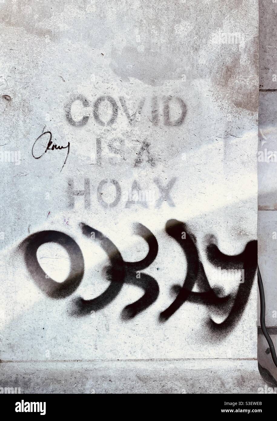 Covid is a hoax okay graffiti Stock Photo