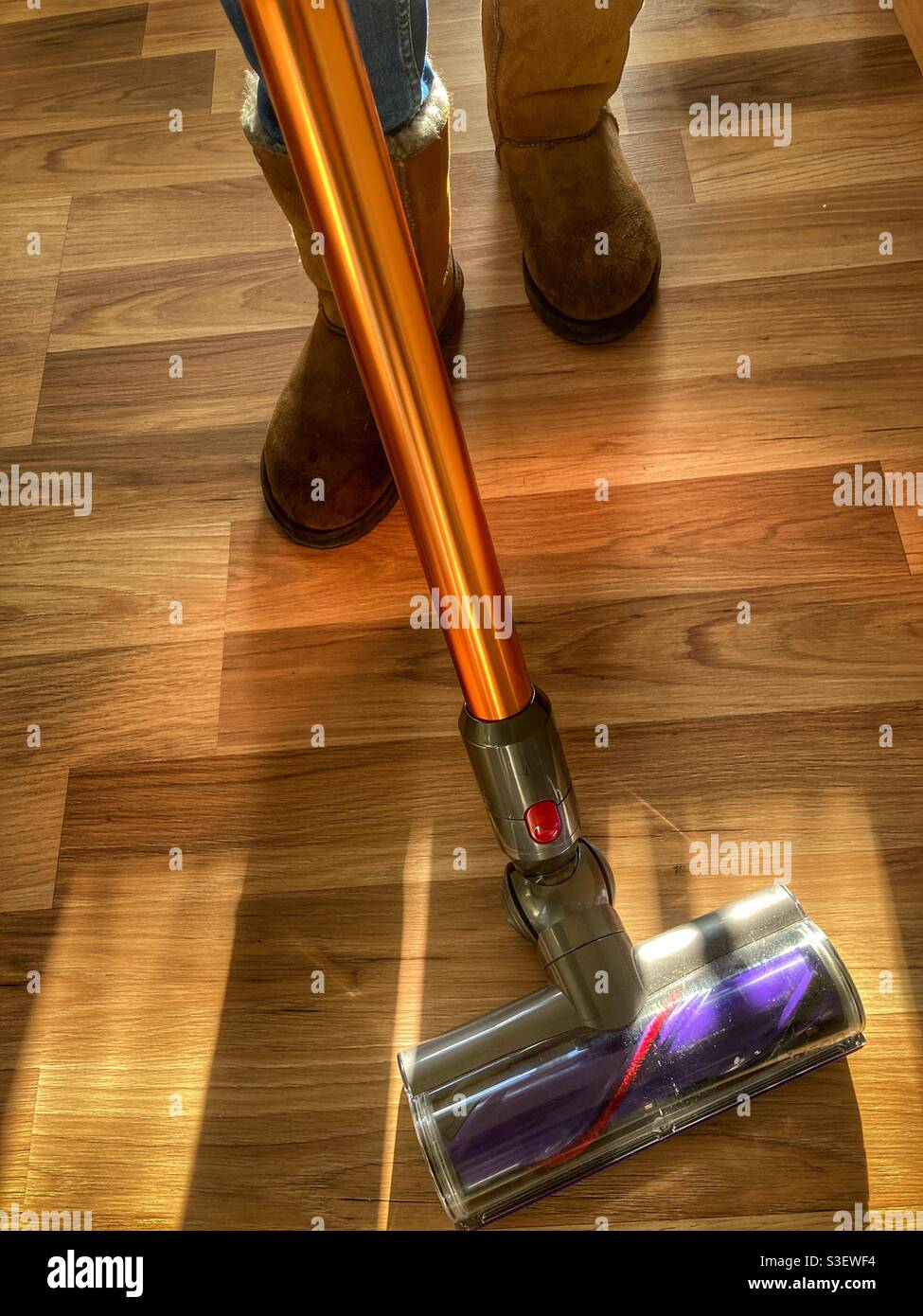 Household chores. Person vacuuming wooden floor. Stock Photo