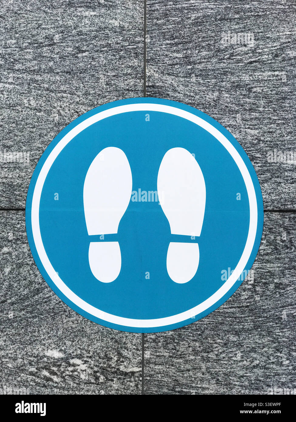 Floor sticker instructing people where to stand during the Covid pandemic. Calgary, Alberta, Canada. - Smartphone Captured Stock Image