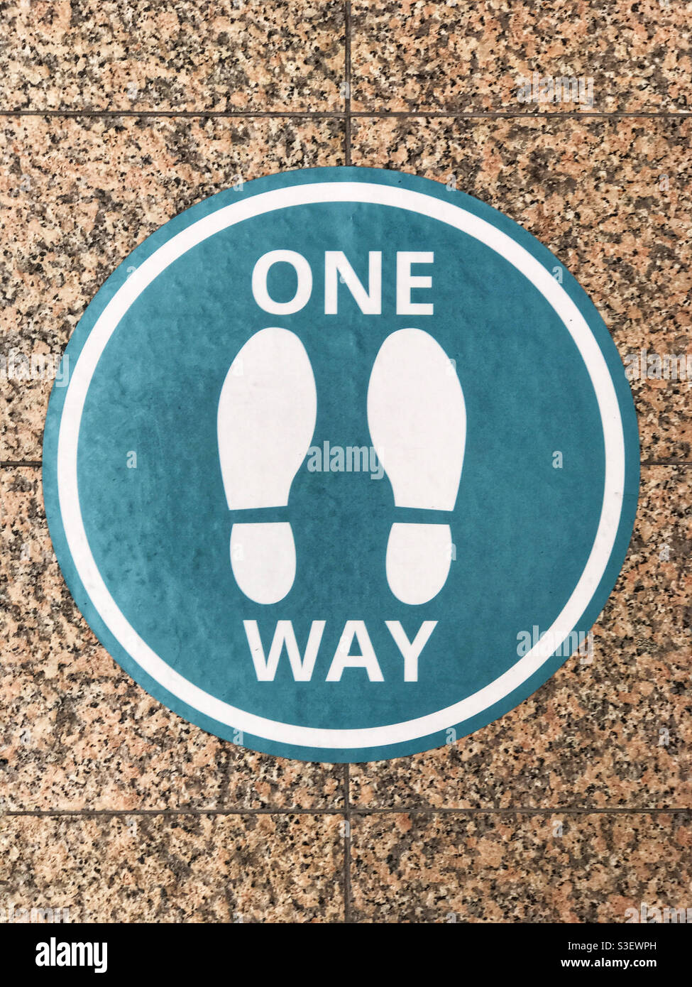 Floor sticker instructing people to walk in one direction in a particular area during the Covid pandemic. Calgary, Alberta, Canada. - Smartphone Captured Stock Image