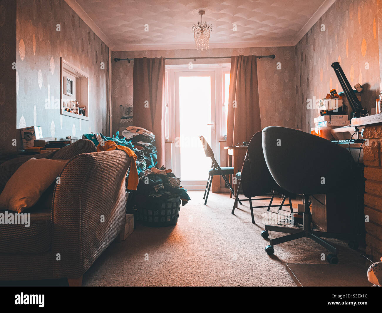 Messy lunge dining room with piles of washed clothes. - Smartphone Captured Stock Image