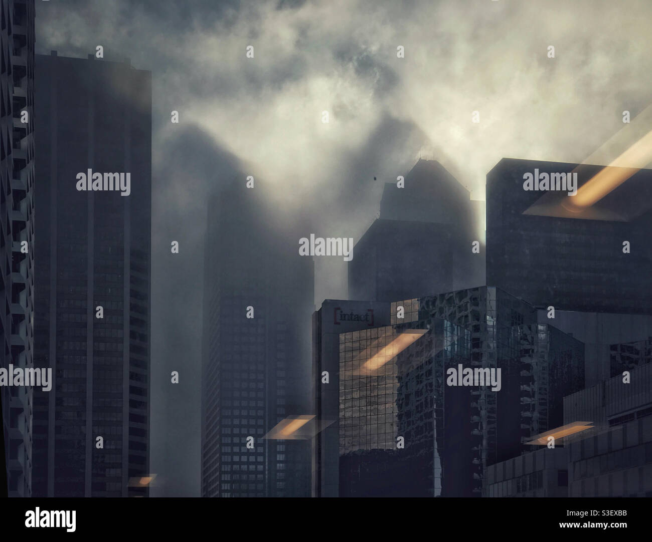 Looking out from an office building at the eerie sight of large building-shaped shadows being cast on the dissipating fog, by the emerging sun. Downtown Calgary, Alberta, Canada. - Smartphone Captured Stock Image