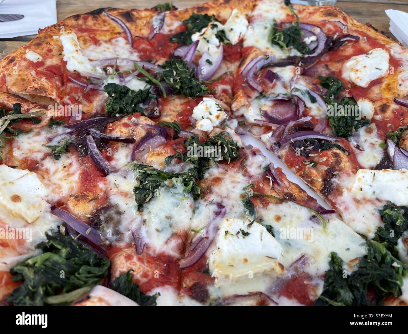 Pizza topped with goats cheese, spinach, tomato and red onion - Smartphone Captured Stock Image