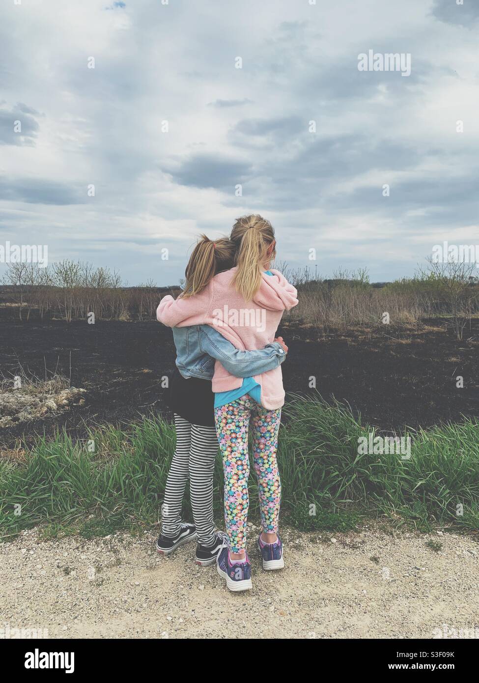 Two young girls hugging outside. Stock Photo