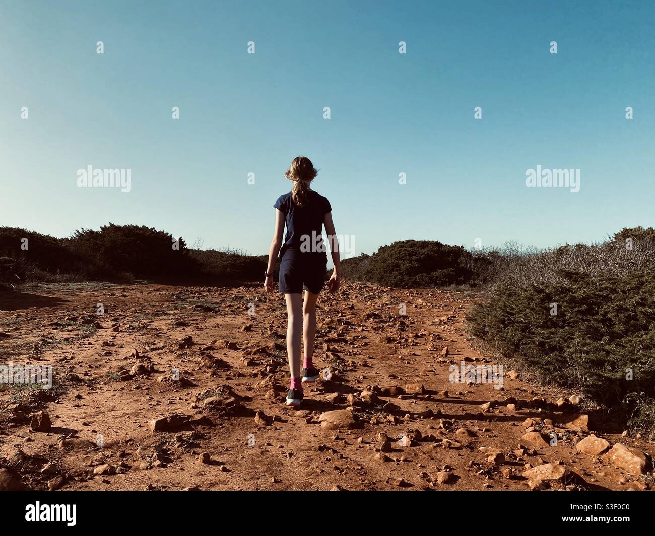 Rear view of girl walking along a rough stony track - Smartphone Captured Stock Image