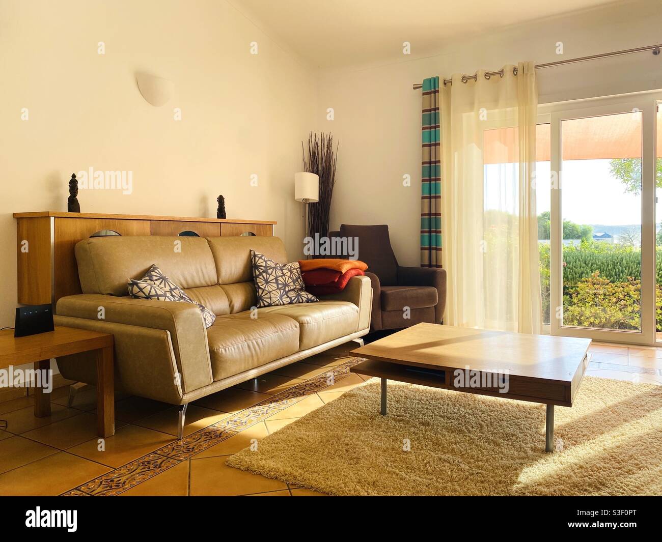 Living room lit by golden sunlight coming through sliding glass doors - Smartphone Captured Stock Image