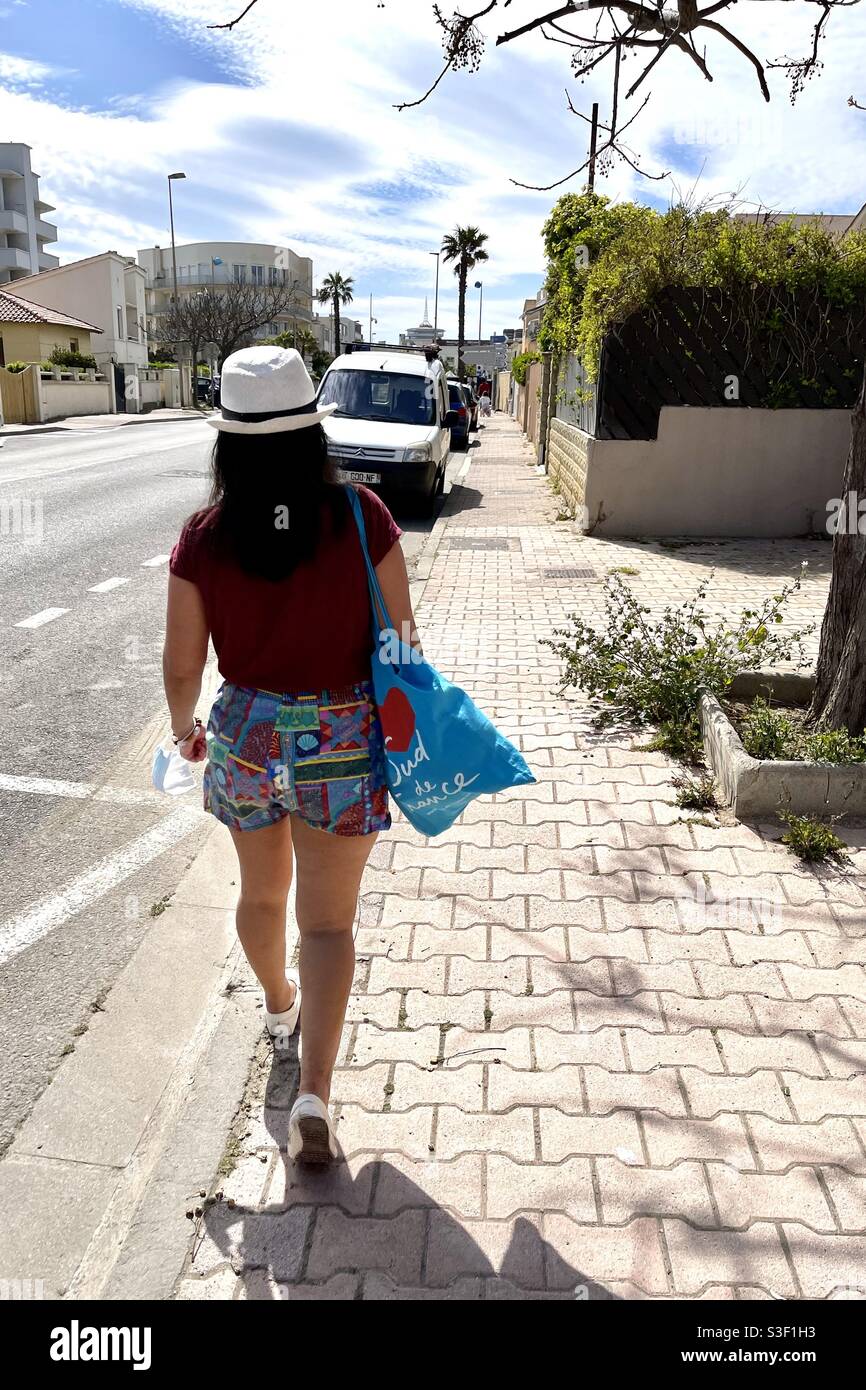 Asian Filipino girl walks along a sunny sidewalk in France - Smartphone Captured Stock Image