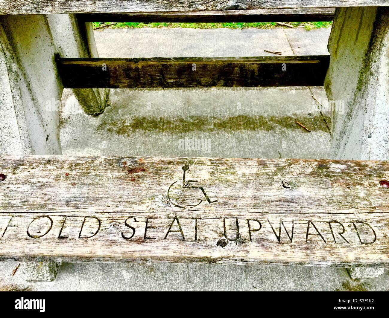 A folding seat with instructions to accommodate wheelchairs at a park bench, Ontario, Canada. Fixed seats on the other side of the table. - Smartphone Captured Stock Image