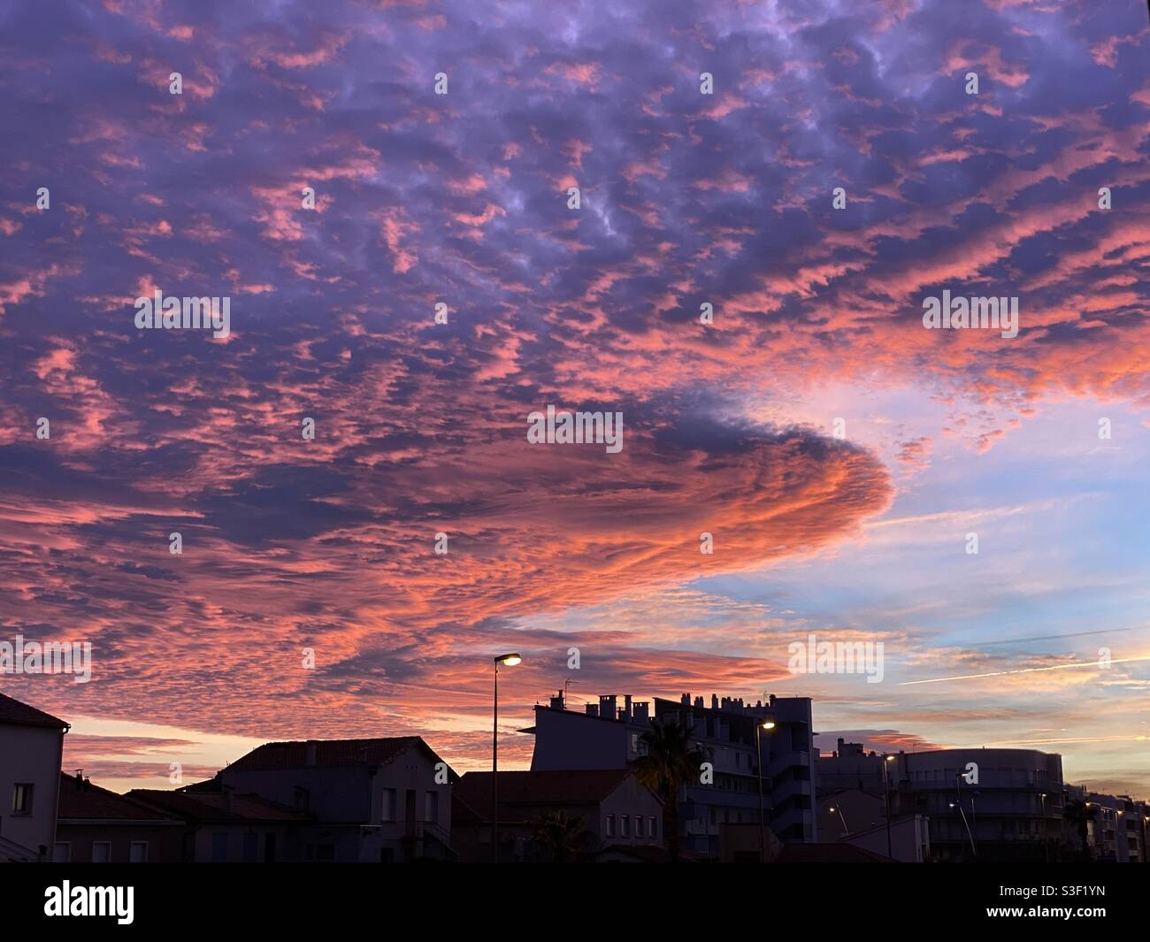 Red orange subset over a city or village skyline in Palavas les Flots, Occitanie, south of France - Smartphone Captured Stock Image