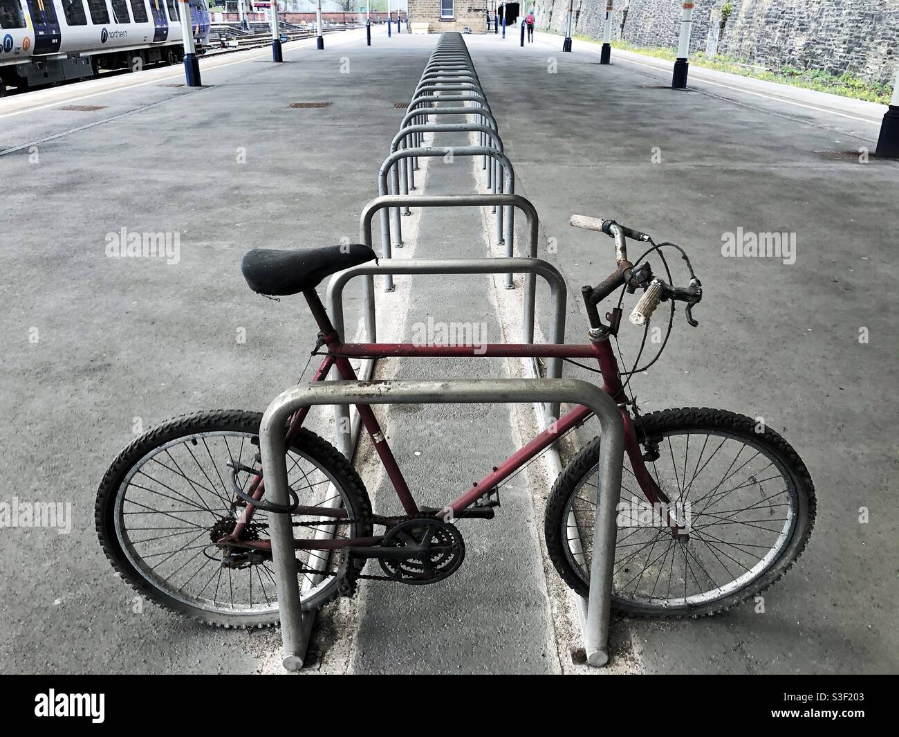 A single bicycle on an empty bike rack on a deserted train station during coronavirus lockdown - Smartphone Captured Stock Image