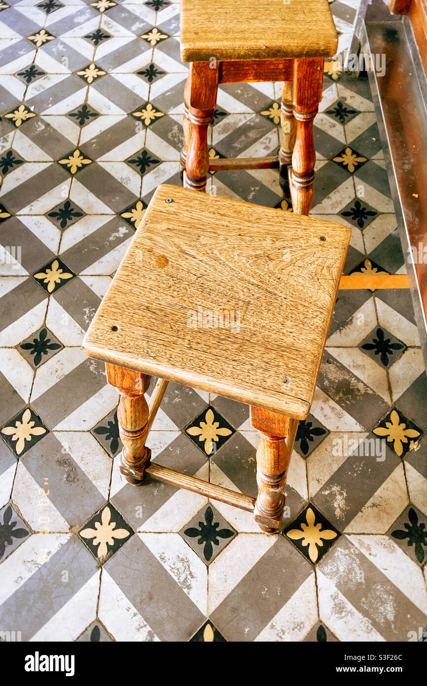 Wooden stool on stucco geometric black and white floor tiles in the south of France - Smartphone Captured Stock Image