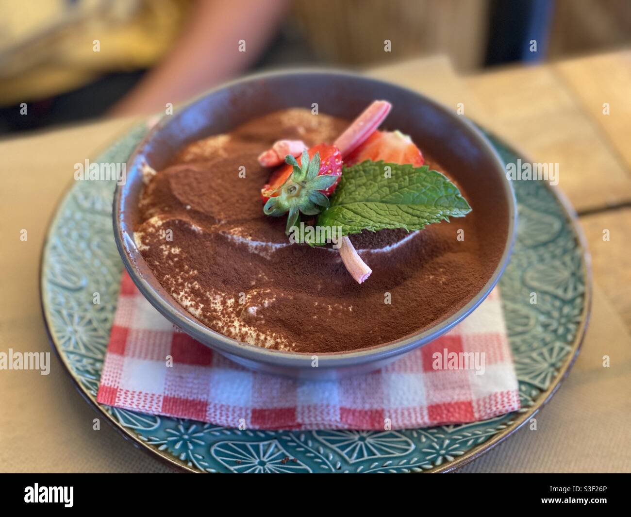 Creamy chocolate candy dessert with mint in a brown bowl on a green restaurant plate - Smartphone Captured Stock Image