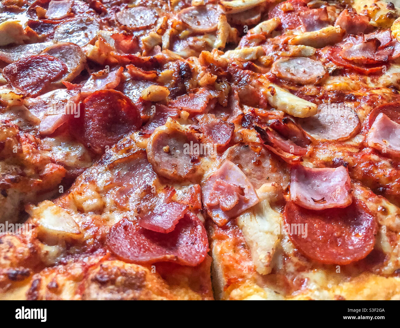 Close up view of a meat feast pizza with bacon, ham, cheese, tomato and pepperoni for topping. - Smartphone Captured Stock Image