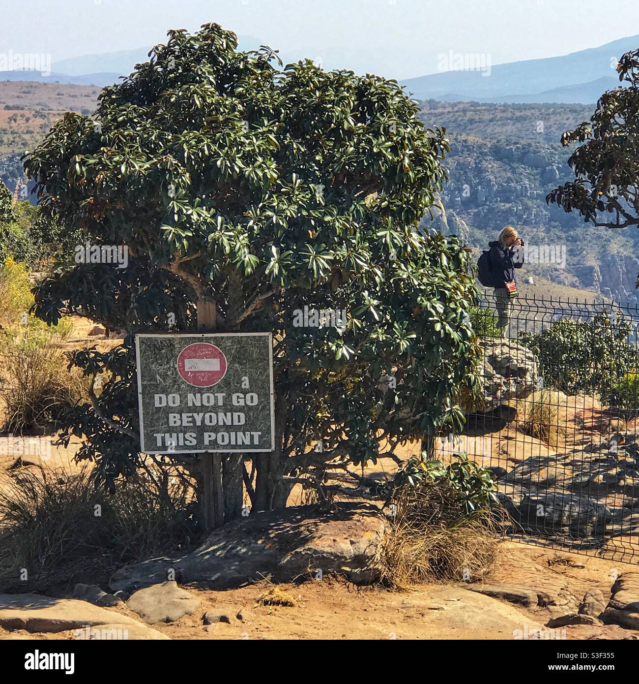 A tourist ignores a warning sign at the Blyde River Canyon in South Africa - Smartphone Captured Stock Image