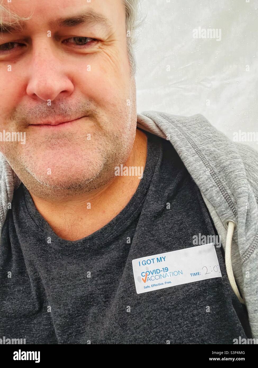 Portrait of a middle aged man after he has received his first shot of the AstraZeneca COVID-19 vaccine in Brisbane, Australia - Smartphone Captured Stock Image