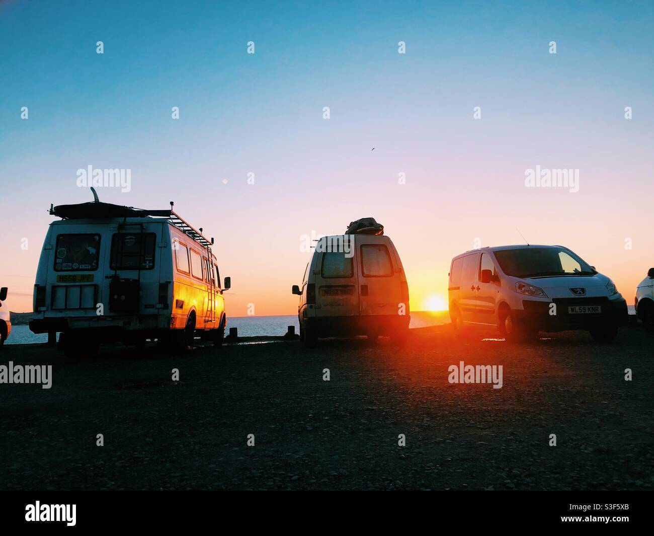Camper vans parked by the  beach at sunset in Cornwall. Van life England - Smartphone Captured Stock Image