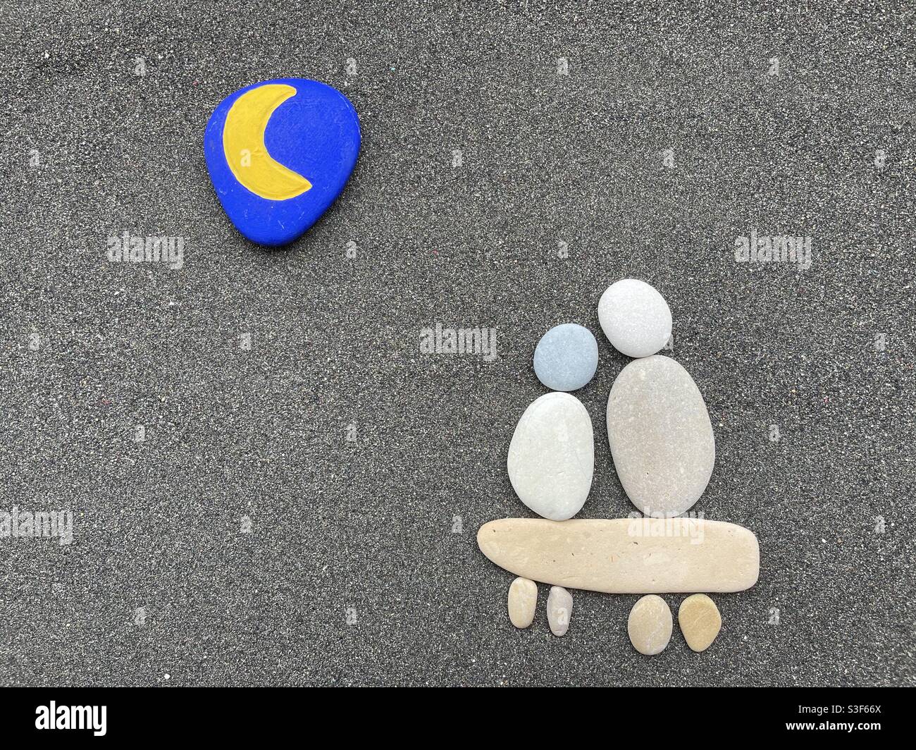 Love under the moon celebrated with a creative composition of stones and pebbles over black volcanic sand Stock Photo