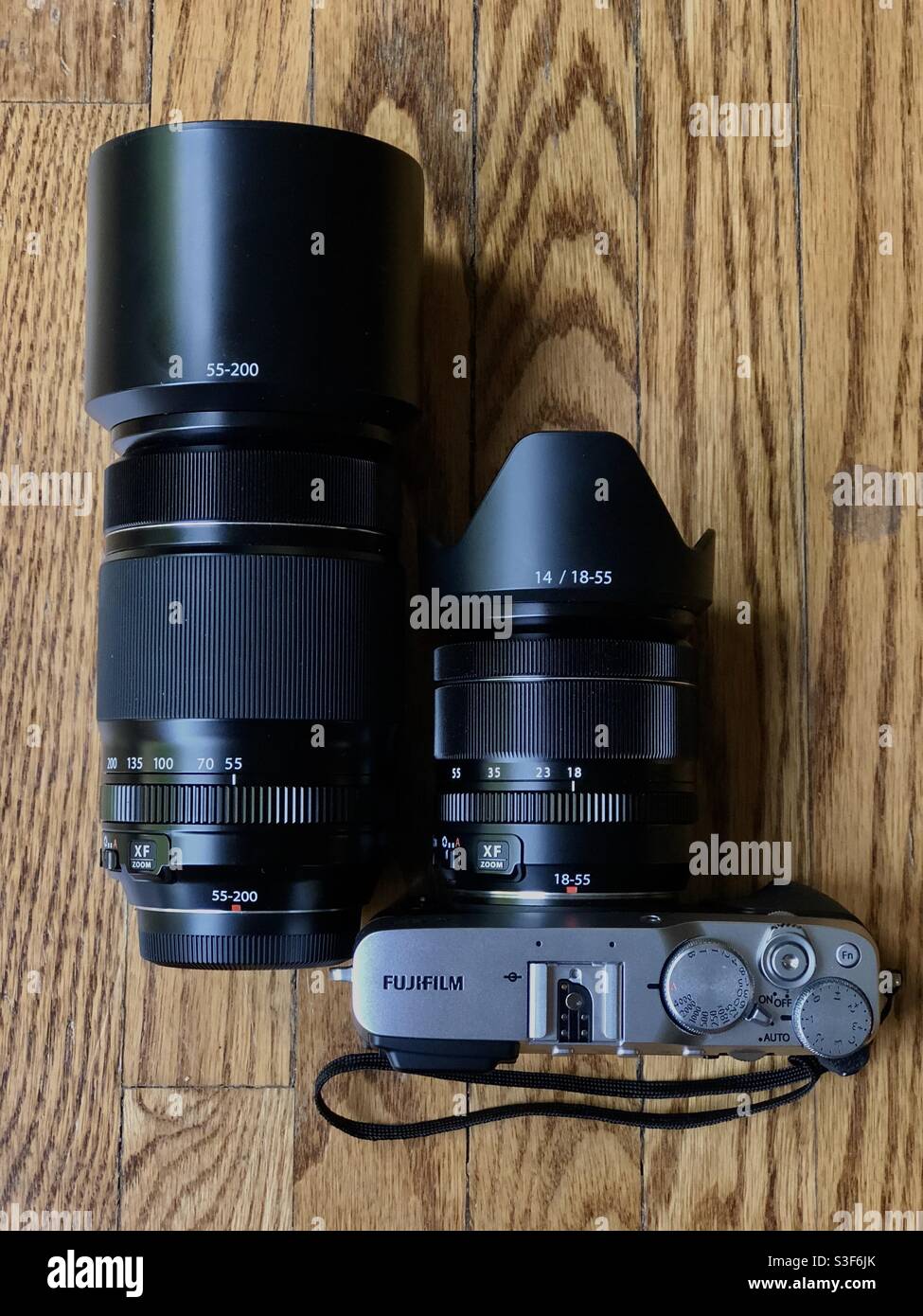 Fujifilm X-E3 rangefinder style digital camera kit with a 18-55mm standard wide zoom and a 55-200 telephoto zoom lens on a wooden table top - Smartphone Captured Stock Image