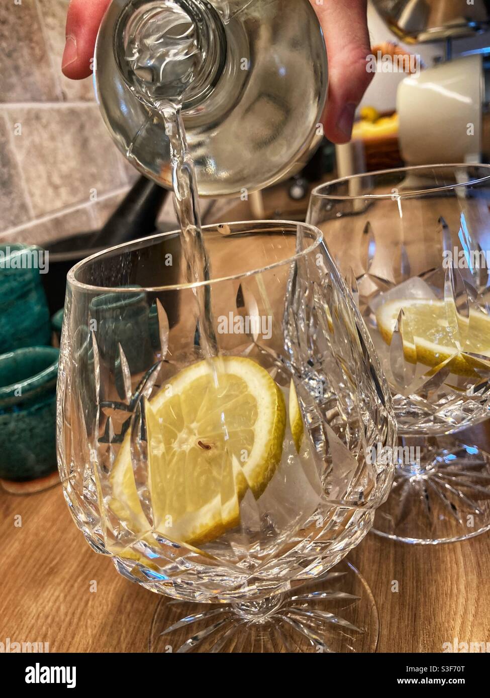 Making gin and tonic filling cut glasses with lemon slices and ice